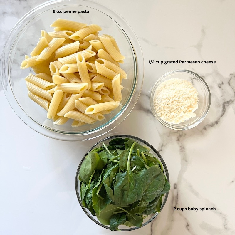 Creamy Sausage Penne Pasta image with cooked pasta, spinach, and grated Parmesan