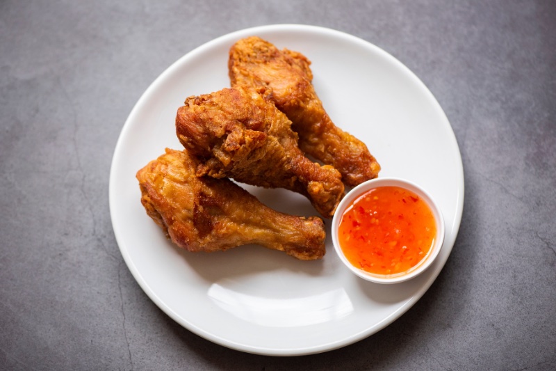 Crispy Fried Chicken on a white plate with sweet and sour dipping sauce on the side. 