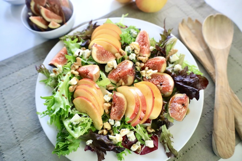 fig salad on a plate next to salad tosser