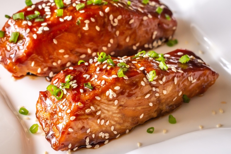 2 teriyaki salmon fillets on a white plate