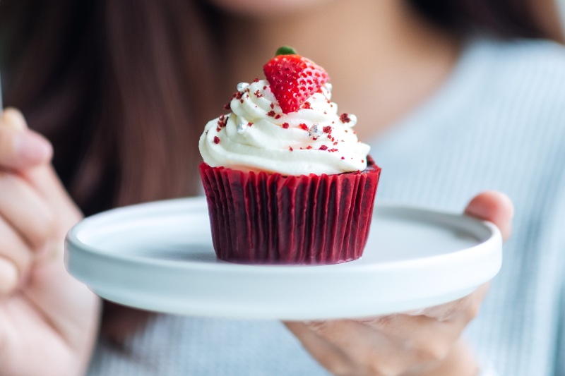 Red Velvet Cupcake on a white plate, the lady is holding
